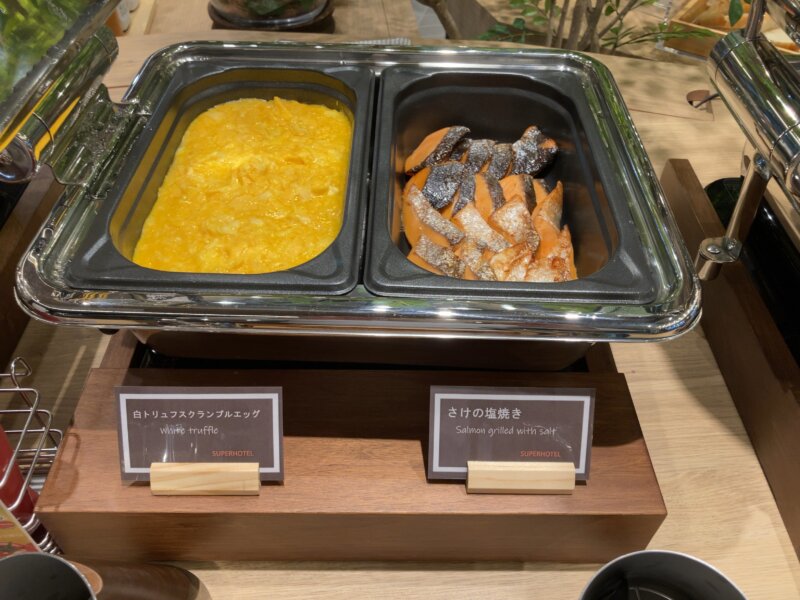 「スーパーホテル Premier 仙台国分町」の朝食で提供された料理（「白トリュフスクランブルエッグ」、「鮭の塩焼き」）