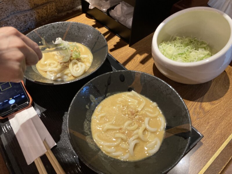 「クリーミーカレーうどん」にネギをトッピングする様子